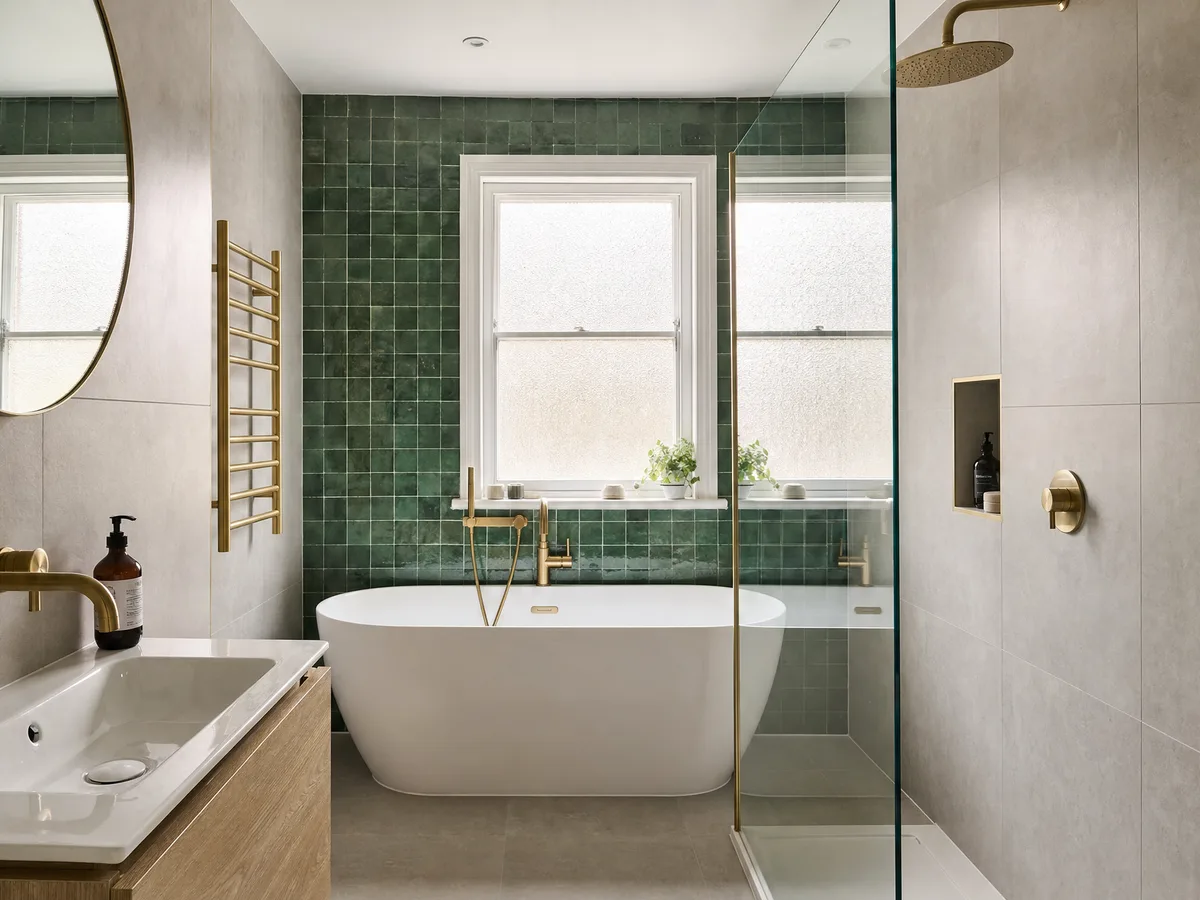 A finished bathroom design with a freestanding bath under a window, green glazed tiles and an oak vanity unit
